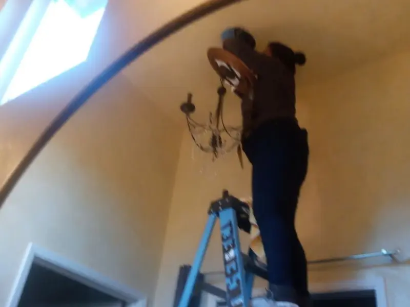 Electrician installing a chandelier in a Phelan residence